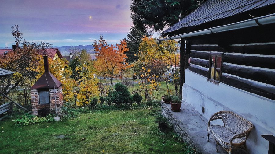 Zahrada s udírnou a barevnými stromy na podzim, vedle roubená stěna